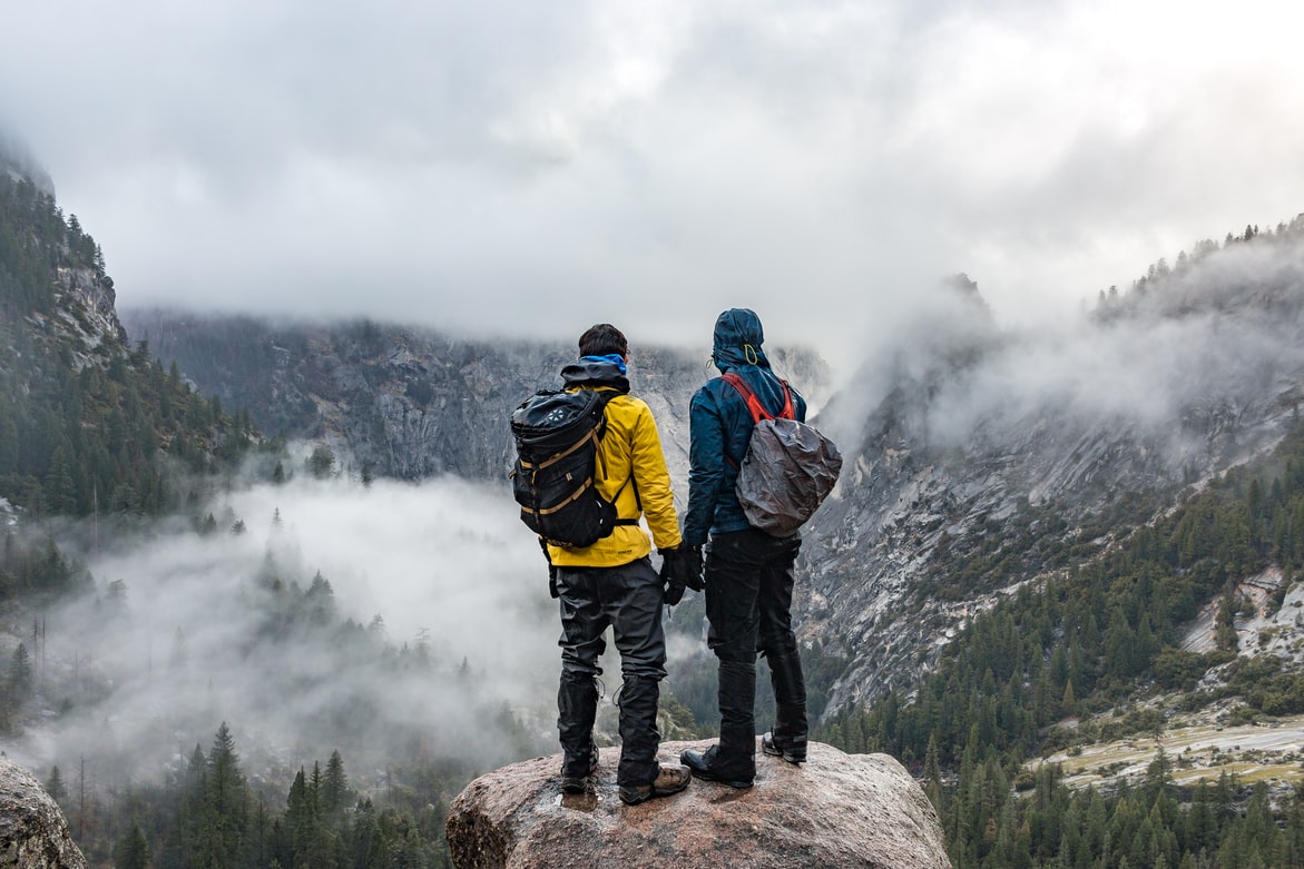 two guys ontop of mountain with fog view